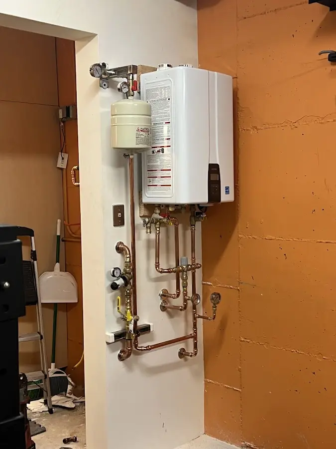 Plumbing technician inspecting water heater connections in Le Sueur